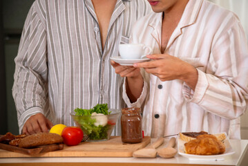 Obraz na płótnie Canvas Happy gay couple enjoy breakfast in kitchen drinking coffee. Two best friends LGBTQ relation partner home cooking. Happiness romance homosexual marriage lifestyle. Two men together love friendship.