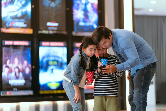 Father and son are using movie tickets to check and chat before going in.