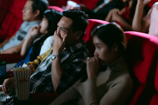 Asian couple crying in the cinema, being sad.