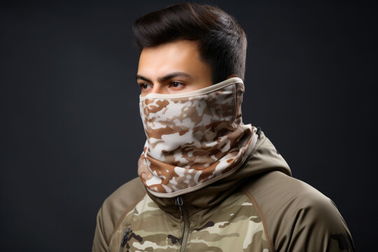 Man wearing a camouflage jacket and a scarf around their neck. The jacket is a mix of brown, beige and green colors