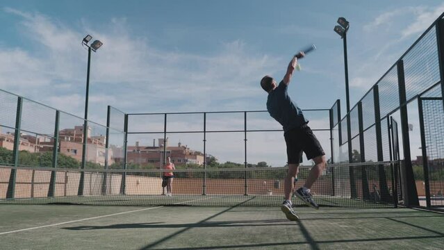 Padel tennis player smashes the ball to win the point in a padel match. Wide shot.