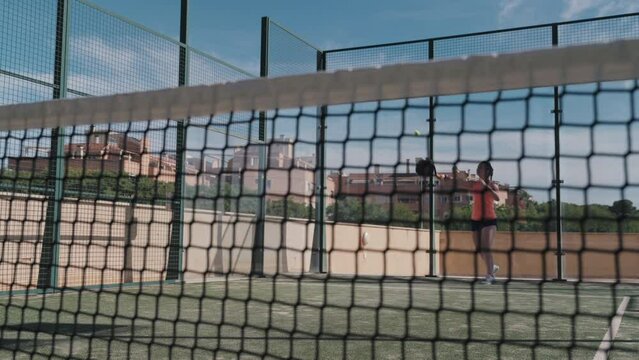 Padel tennis player does a drive shot. Net view.
