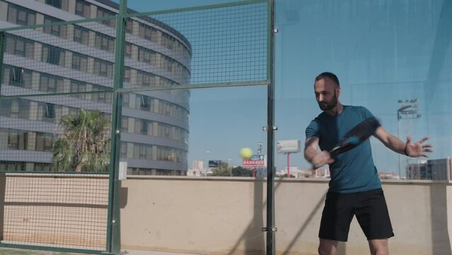 Padel tennis player does a handback shot.