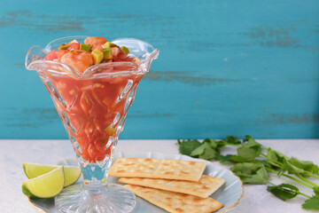 青背景のメキシコ料理のセビーチェ・アカプルケーニョ　塩味のクラッカーをそえて　コピースペースあり  Mexican food Ceviche acapulqueño（Cebiche acapulqueño, Ceviche estilo Acapulco) served with salty crackers, on blue background copy space available