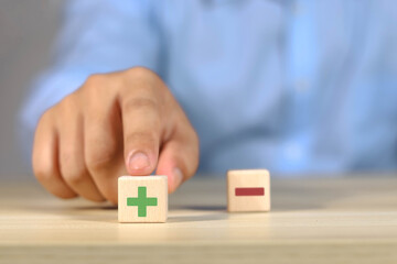 Wooden blocks showing plus and minus signs. The concept of antithesis. Decision making. Positive or...