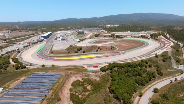Drone pullback to sky reveals portimao circuit and red yellow lanes, blue sky day