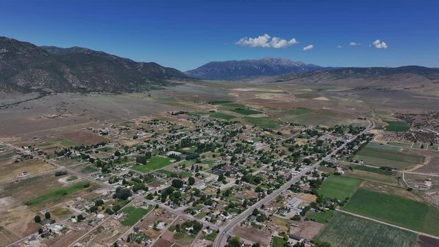 Aerial agriculture farm town mountain valley high. Farming community agricultural economy. Spring summer weather mountain valley green agriculture field. Homes, barns and buildings.