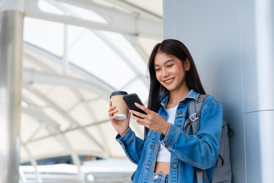 Young asian woman standing and using smartphone on the street - Powered by Adobe