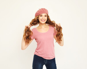 Obraz na płótnie Canvas Beautiful young woman with long wavy hair wearing pink beret over grey background