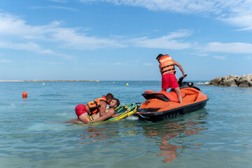 Lifeguards rescue a man in the sea using a jet ski