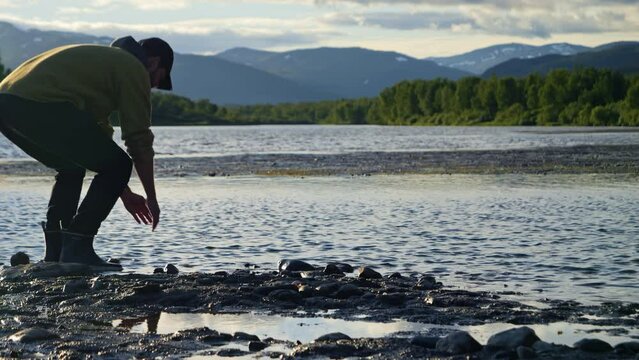 Person drinks Clean fresh water from freshwater lake in Lapland, Scandinavia, Northern Europe, medium wide shot