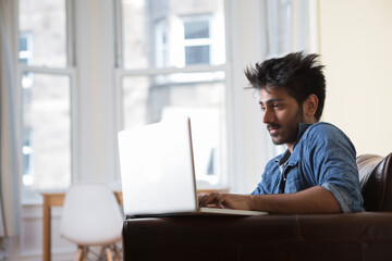 Fototapeta premium Indian man using Laptop at home in the lounge.