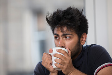 Indian man at home with a mug of hot drink.