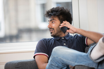 Indian Man using his phone at home.