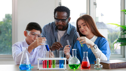 male and female students with various colored liquid glass vials with instructors to advise in the laboratory
