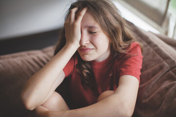 Fototapeta premium Sad thoughtful teen girl sits on couch