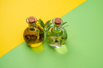 Olive concept, extra virgin olive oil flasks with olive tree leaves on a yellow and green background
