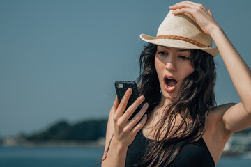 surprised girl on the beach looking at the mobile phone