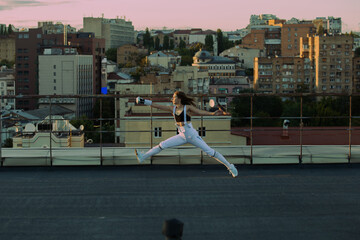Two fencers woman practice on a rooftop with the city in the background.