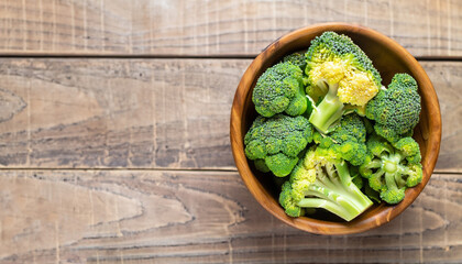 Fresh green broccoli in wood bowl over rustic wooden background - healthy or vegetarian food concept Top view.