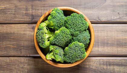 Fresh green broccoli in wood bowl over rustic wooden background - healthy or vegetarian food...
