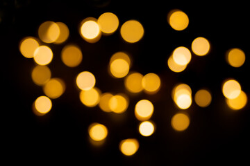 Yellow and brown defocused lights on black background. Blurred bokeh, overlay. Christmas, New Year, holiday