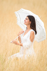 romantic scene with young pretty fiancee with umbrella and dress