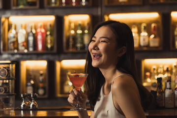 Asian women drinking cocktails and having fun at the bar at night.