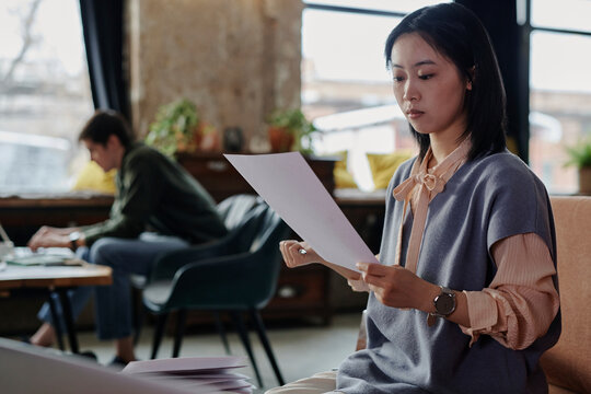 Young businesswoman reading document in cafe