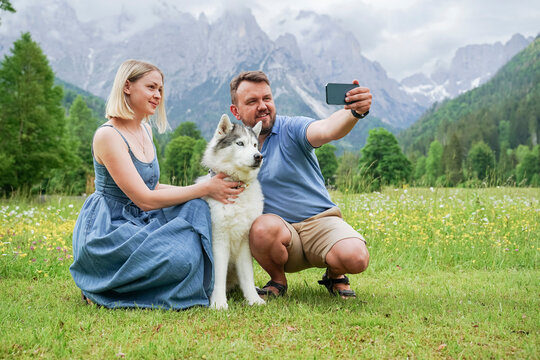 Man and woman taking selfie with dog through smart phone