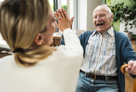 Cheerful father giving high-five to daughter at home