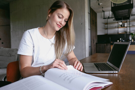 Smiling freelancer reviewing file sitting at desk in home office