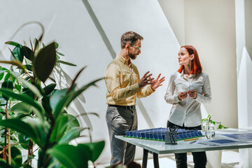 Businessman explaining and having discussion with colleague over solar panel model in office