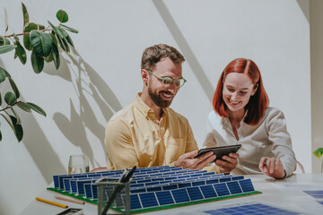 Happy business colleagues using tablet PC at desk in office