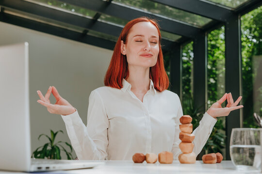 Smiling businesswoman with eyes closed meditating at desk in office