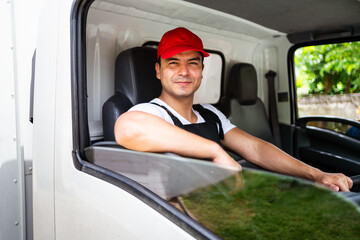 Happy professional truck driver with his assistant wearing a red cap, smiling, looking at the...