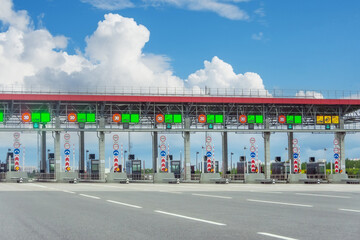 View gate for cars at the entrance to the toll road, limited by the barrier. Cashless payment transponder, speed limit signs. © aapsky