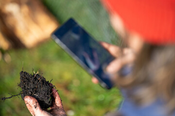 Female Farmer using technology to test soil. Farmer taking a photo of a soil sample. Holding soil in a hand