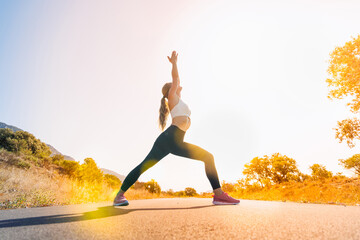 young woman doing yoga in nature on sunrise road- sport,flexibility,active lifestyle,stretching...