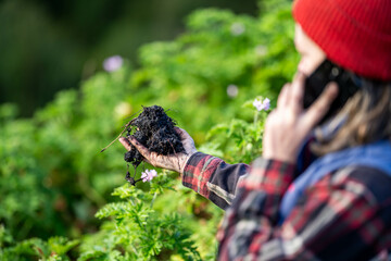 Female Farmer using technology to test soil. Farmer taking a photo of a soil sample. Holding soil in a hand
