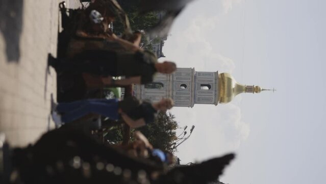 Ukraine, Kyiv - May 24, 2023: Saint Sophia Cathedral in Kyiv Ukraine with people walking on street and blurred destroyed tank guns at front. Bravery and courage concept. Vertical orientation video