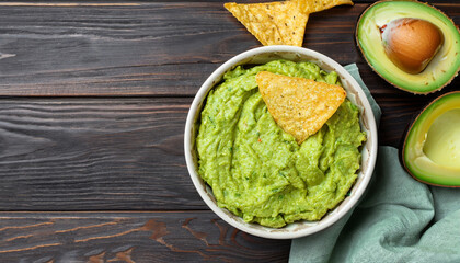 Fresh guacamole dip with chips on dark wooden background. Food and vegetarian concept. Top view. - obrazy, fototapety, plakaty
