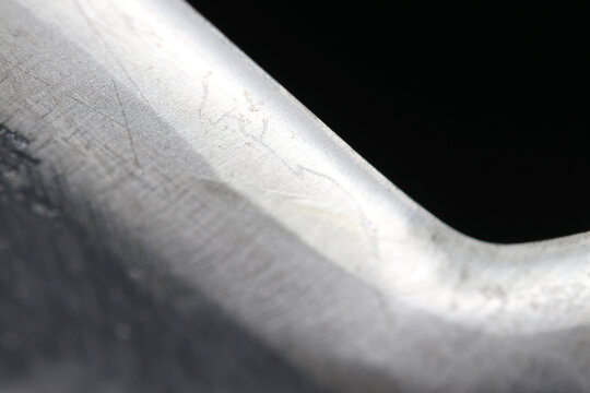 かぎ爪状に刃先が曲げられている日本の鉈の刃先（黒バックに葉先が光る接写画像）