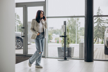 Woman talking on the phone and walking in a car showroom looking for a new car