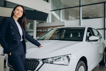 Fototapeta na wymiar Sales woman in a car showroom standing by white car