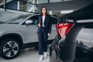 Sales woman in a car showroom standing by the car