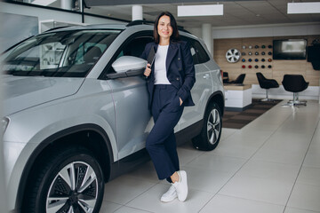 Sales woman in a car showroom standing by the car