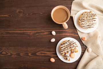 Tartlets with meringue cream and cup of coffee on brown wooden, top view, copy space.