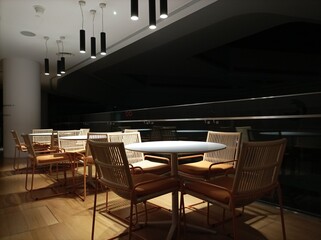 Modern interior design in a building room with Low light photography at night. Tables and chairs under the light with dark background.
