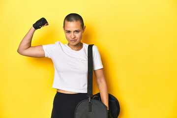Athletic woman with gym bag, gloves, showing strength gesture